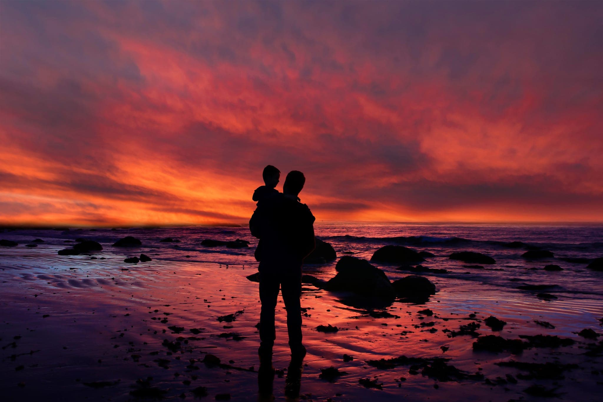 Parent holding a child at sunset