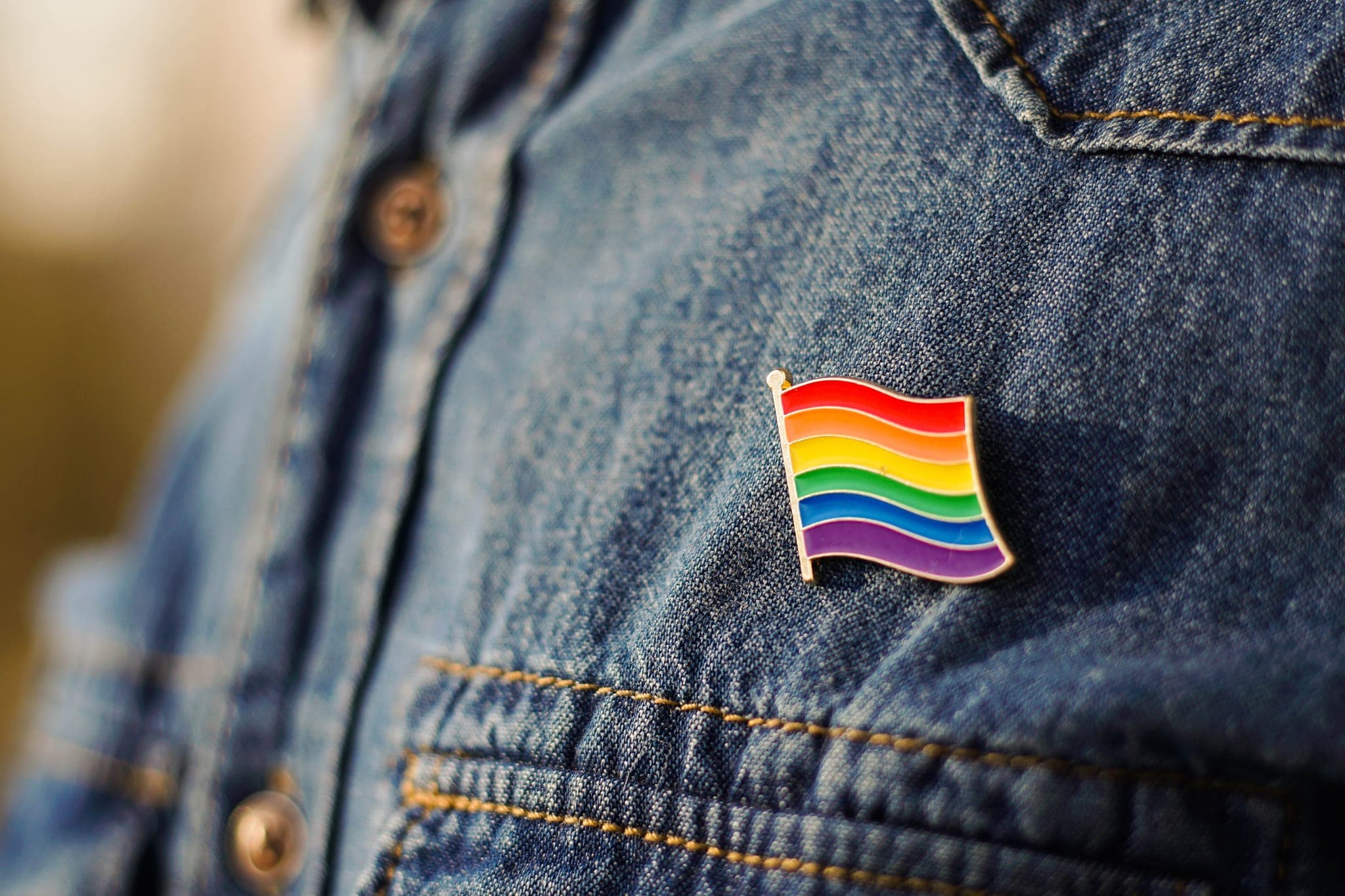 Rainbow flag pin on a denim jacket