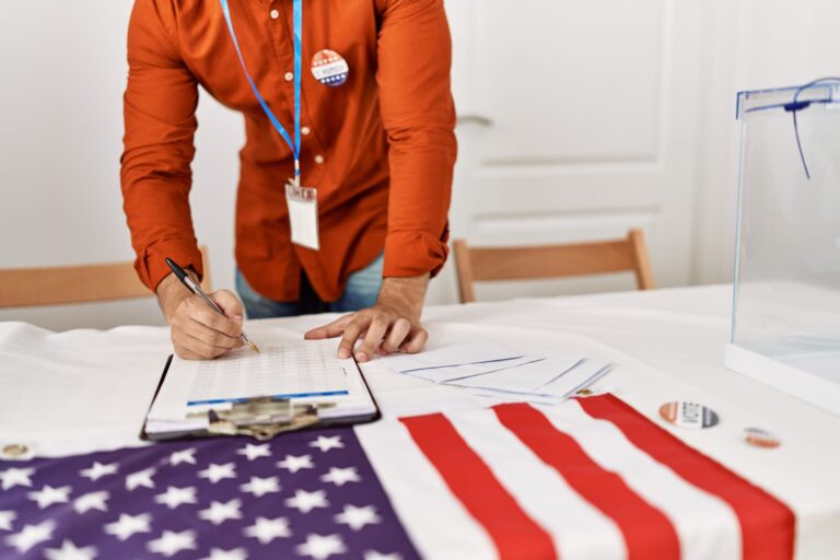 Election worker completing voter registration paperwork beside an American flag